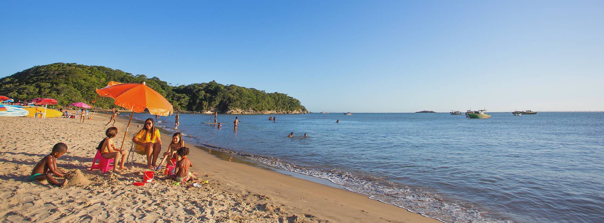 Foto de uma família curtindo a Praia Boca da Barra num dia ensolarado