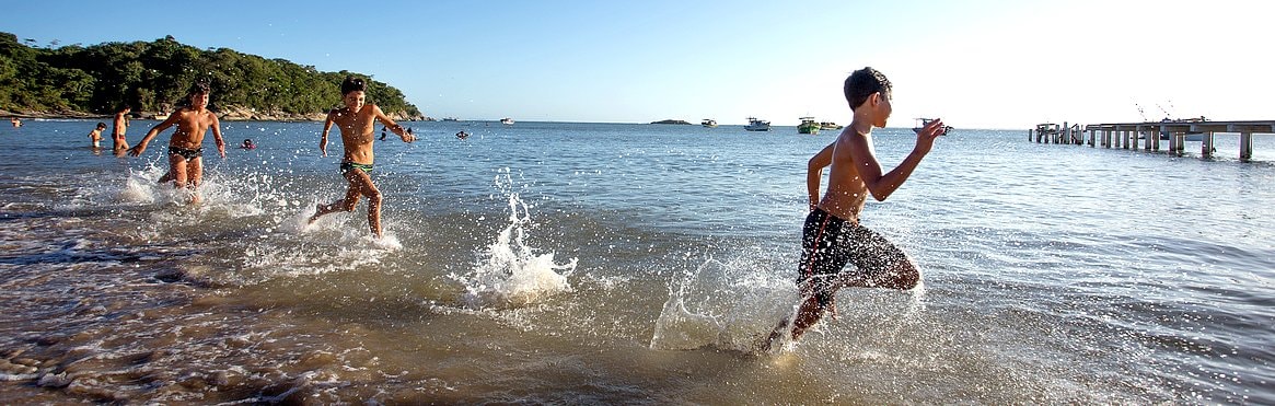 Fotos de várias crianças correndo na beira da água na praia