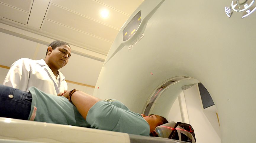 Foto de um profissional de saúde acompanhando uma paciente durante o exame de tomografia