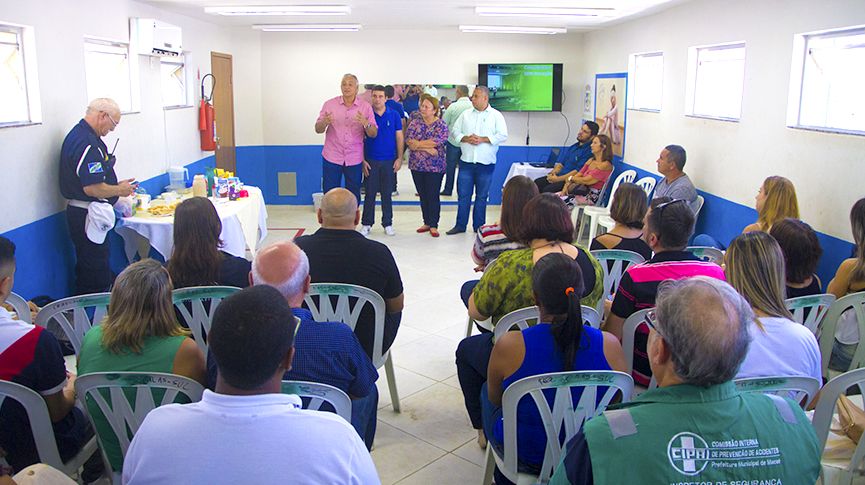 Foto do Prefeito Carlos Augusto ao lado da secretária de Bem-Estar Social, Elizabeth Bousquet conversando com dezenas de pessoas numa sala