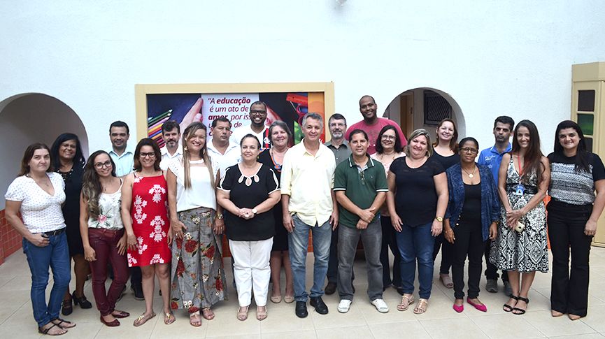 Foto do secretário de Educação Cezar Santa Ana posando para foto ao lado de vários outros profissionais da educação