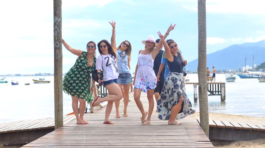 Foto de cinco jovens mulheres posando para foto no pier da praia do centro