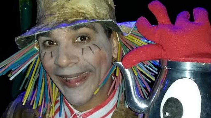 Foto de personagem da peça fantasiado segurando um bule