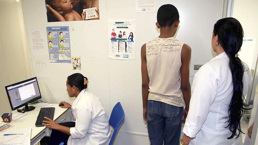 Foto de profissionais de saúde pesando um adolescente