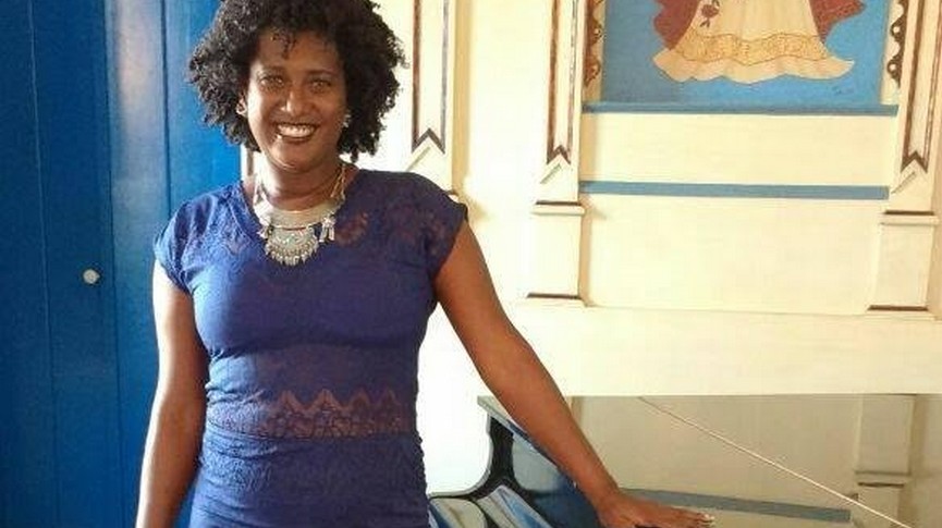 Foto da artista Dada Trindade ao lado de um piano
