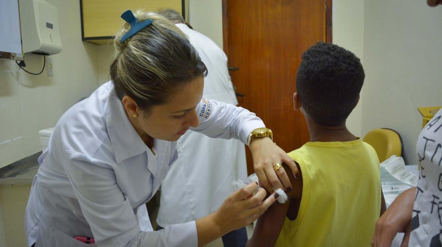 Enfermeira aplicando a vacina em uma criança