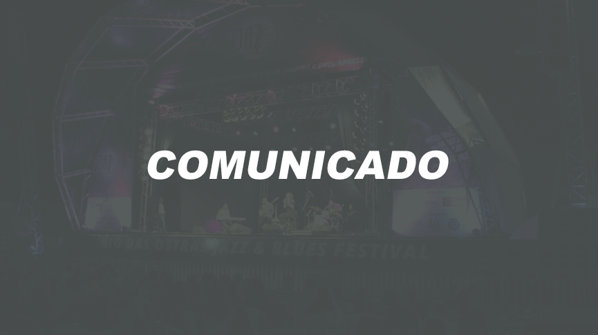Foto do palco principal ao fundo e comunicado escrito em primeiro plano