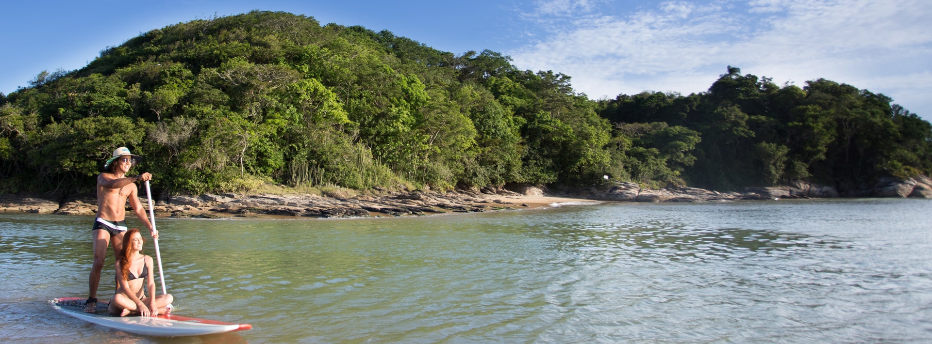 Foto de um casal na praia da Boca da Barra em um stand up paddle