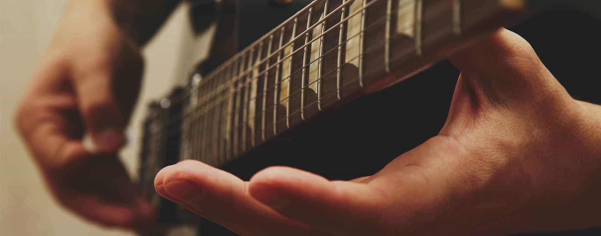 Foto em close de uma mão tocando guitarra