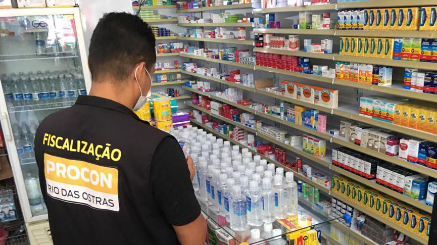 Fiscal com colete vistoria farmácia; no balcão aparecem medicamentos