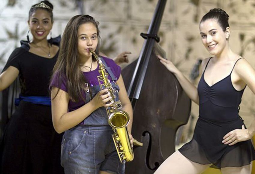 Uma jovem vestida com fantasia, uma jovem com saxofone e uma jovem com roupa de balé