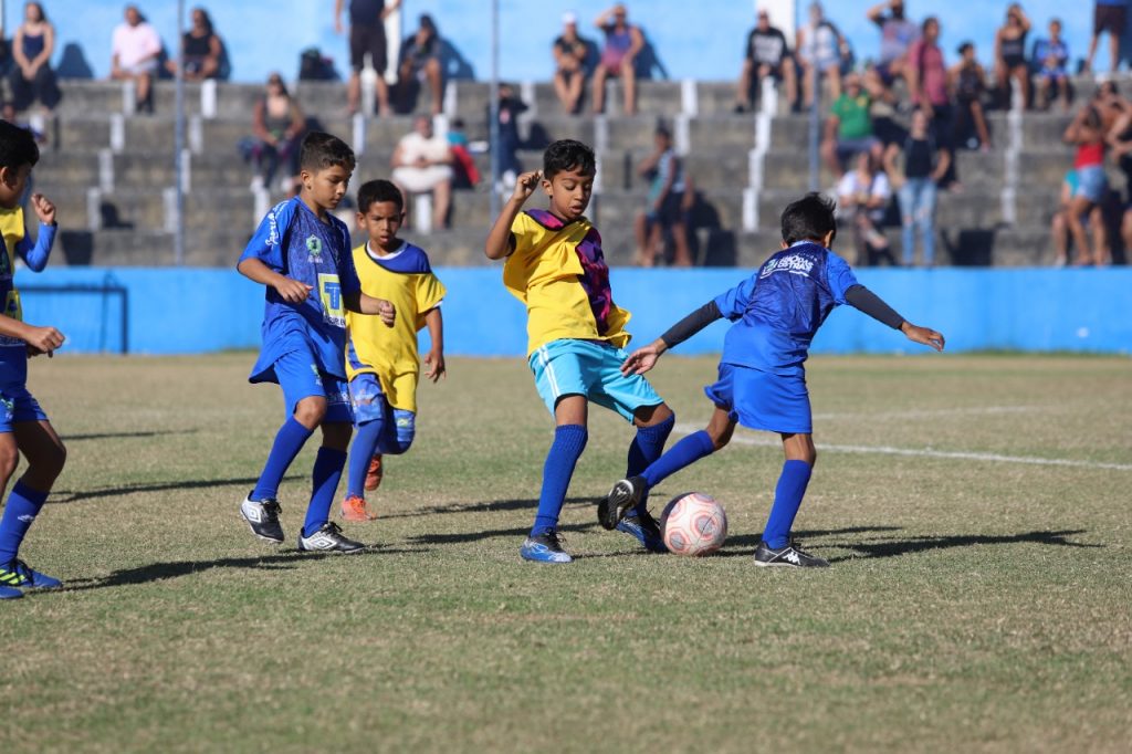 Jogadores da categoria infantil no campo disputando a bola