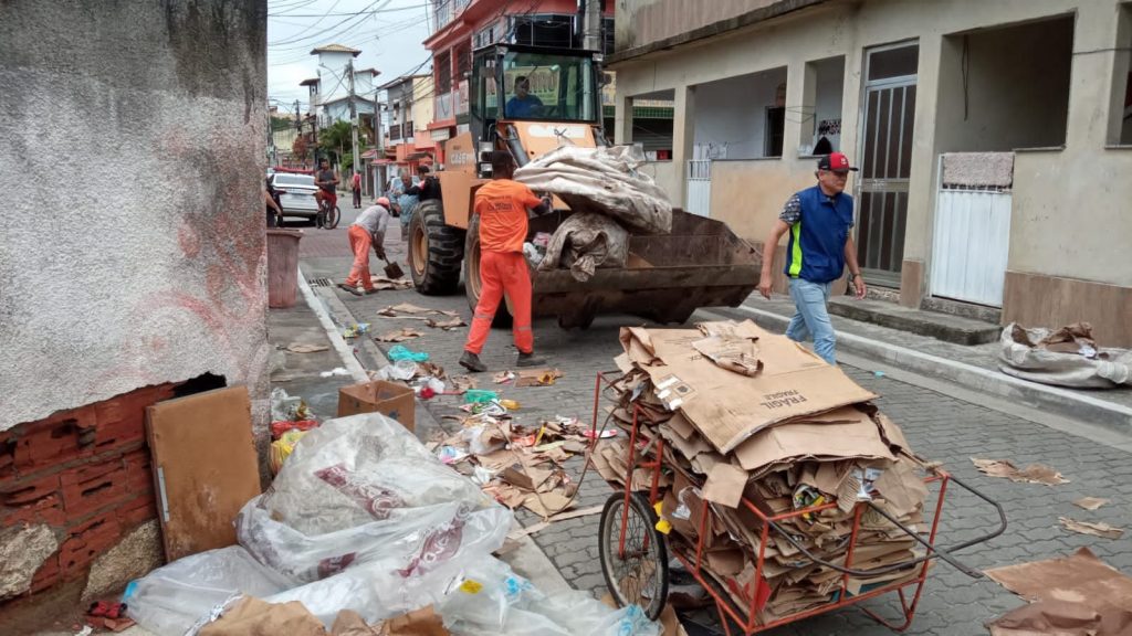 Homens da Limpeza Urbana recolhem em trator entulhos recicláveis que obstruem a rua