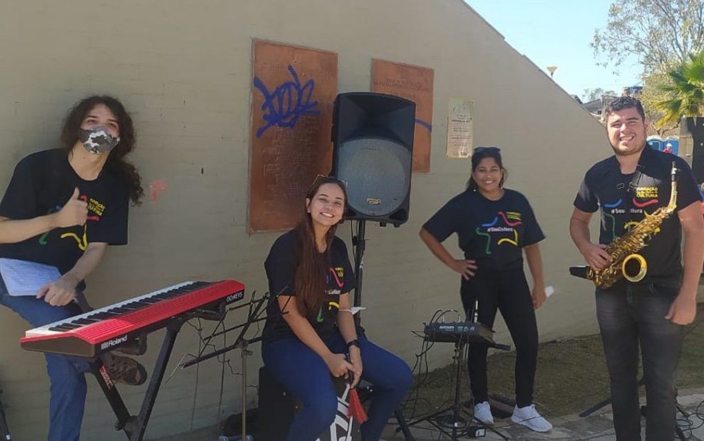 Músicos com instrumentos e as camisas da Fundação de Cultura