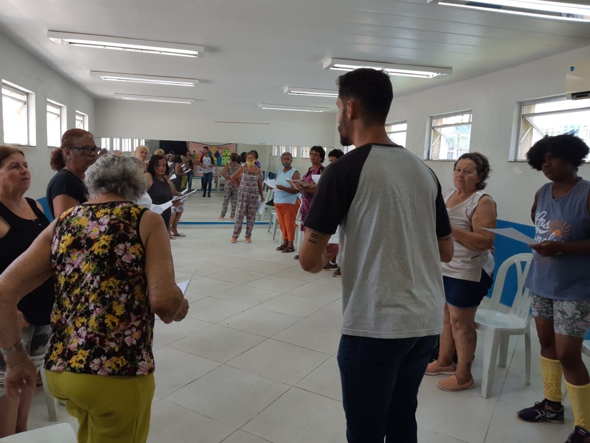 Maestro de pé ensaiando idosos que vão apresentar a cantata de Natal.
