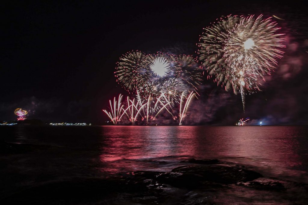 Queima de fogos na praia, com reflexo nas águas do mar
