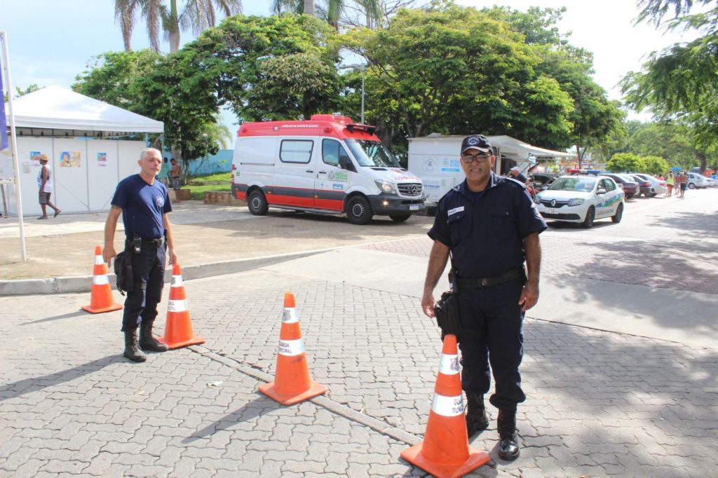 Dois guardas municipais ao lado de cones que bloqueiam rua