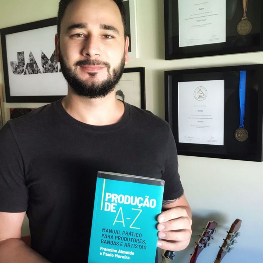Autor em primeiro plano segura o livro mostrando a capa