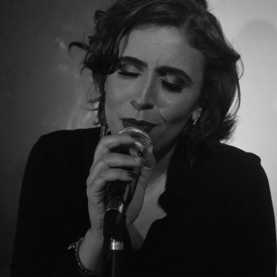 Imagem preto e branca da cantora ao microfone interpretando uma canção