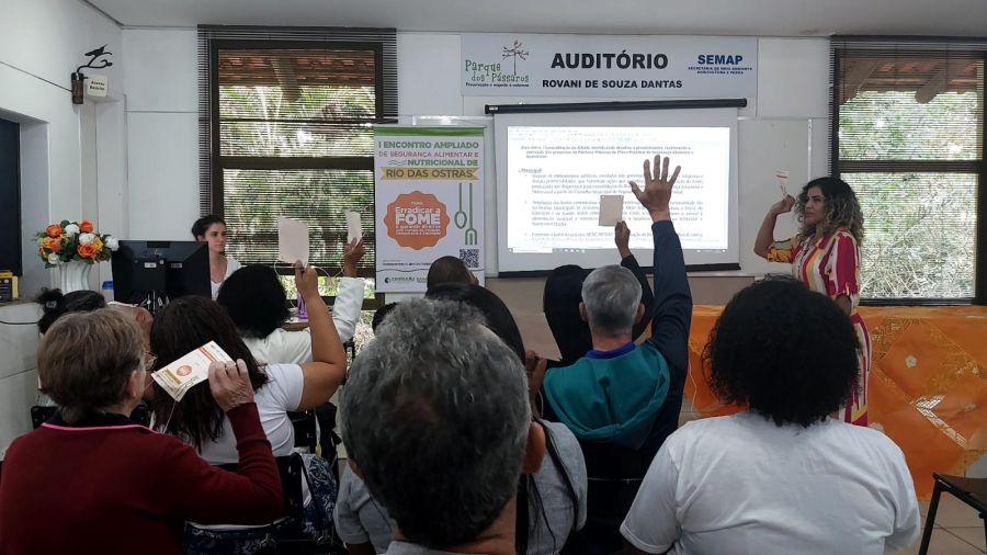 Pessoas reunidas no auditório, levantando as mãos e debatendo assunto relacionados a segurança alimentar