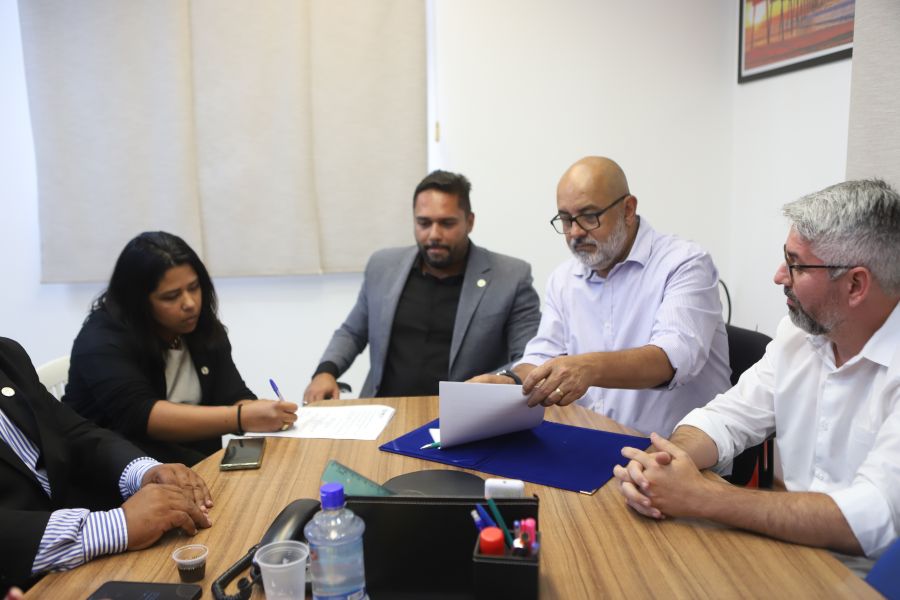 Autoridades, à mesa, assinam documentos