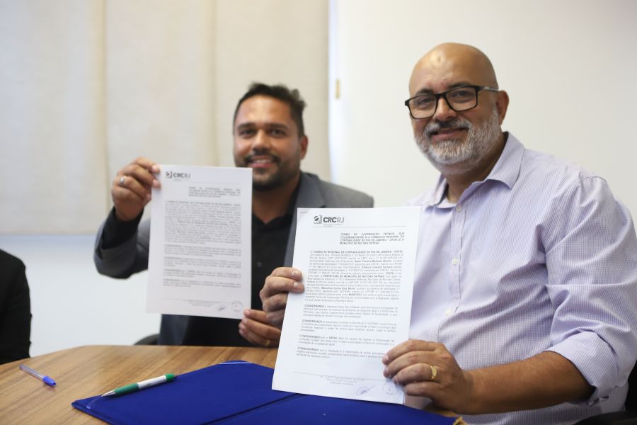 Secretário ao lado de representante do CRC seguram documento assinado