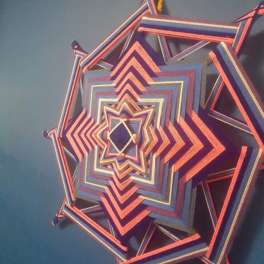 Foto de uma Mandala de cores vermelha e azul produzida por barbantes.