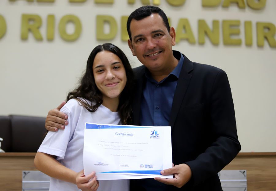 Menina de uniforme do Geração Aprendiz em foto posada ao lado do Maurio Braga Neto, presidente da câmara.