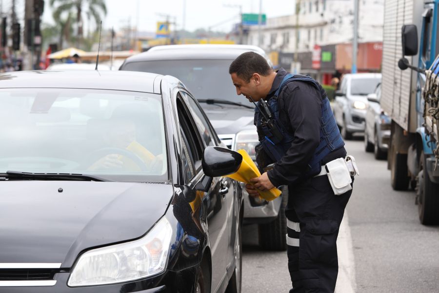 Guarda entrega no sinal a motorista sacola veicular e material informativo sobre o trânsito
