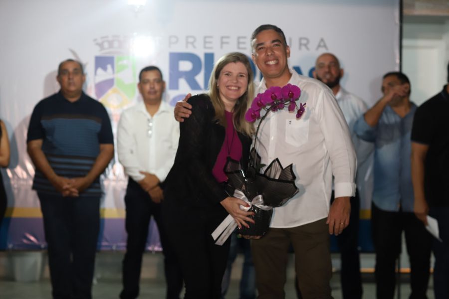 Secretário ao lado de filha do homenageado pelo Capsi, que segura vaso com orquídea