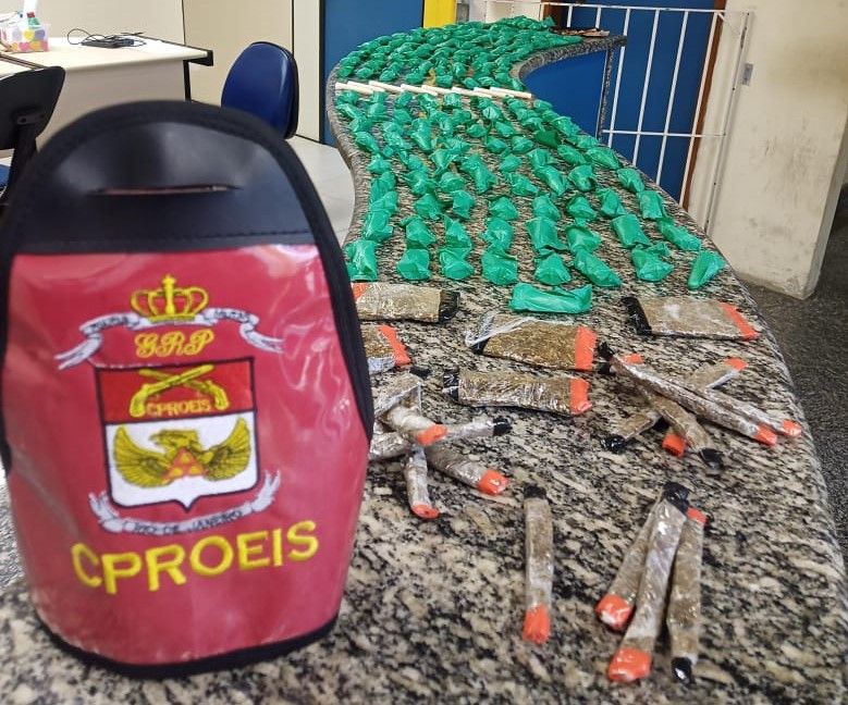 maconha e pinos de cocaína expostos no balcão da delegacia com braçal do CProeis