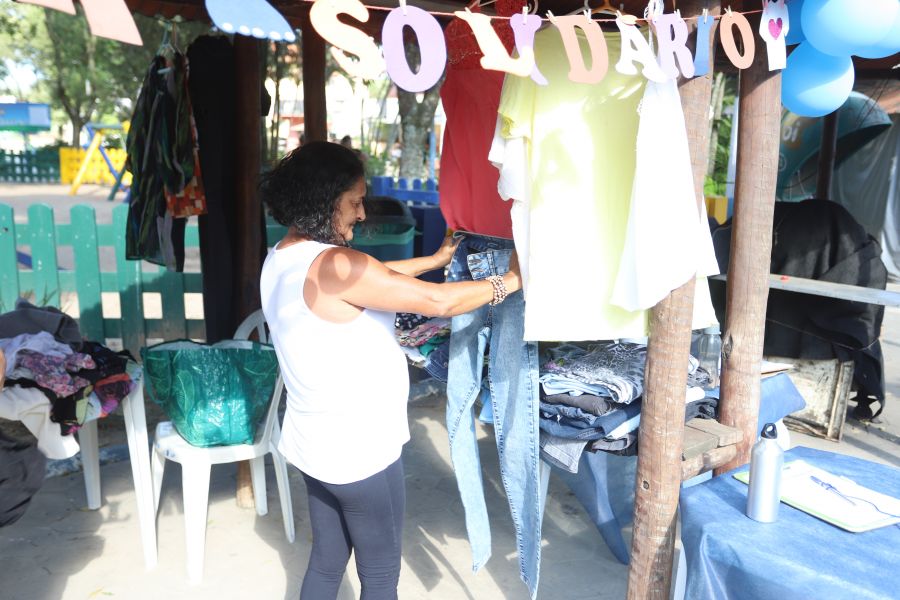 Mulher examina calça no estande do Varal Solidário
