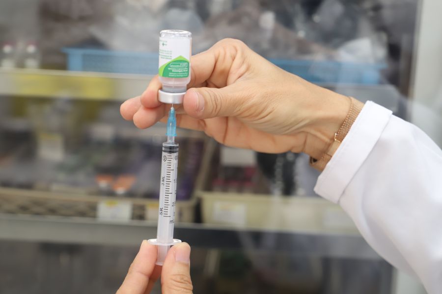 Mão com uma seringa e frasco de vacina