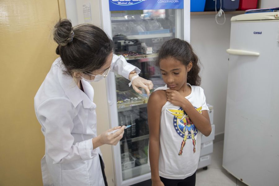 Enfermeira aplicando dose de vacina no braço de uma criança