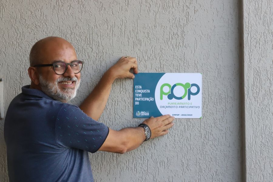 Secretário de Gestão Pública segura placa de obra realizada pelo POP