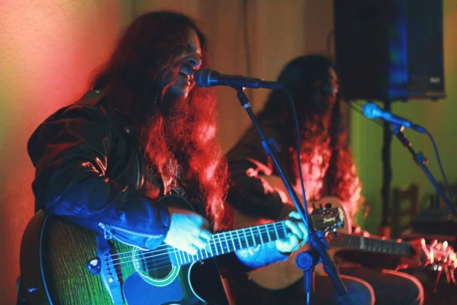 Na foto, dois músicos cantam em seus respectivos microfones