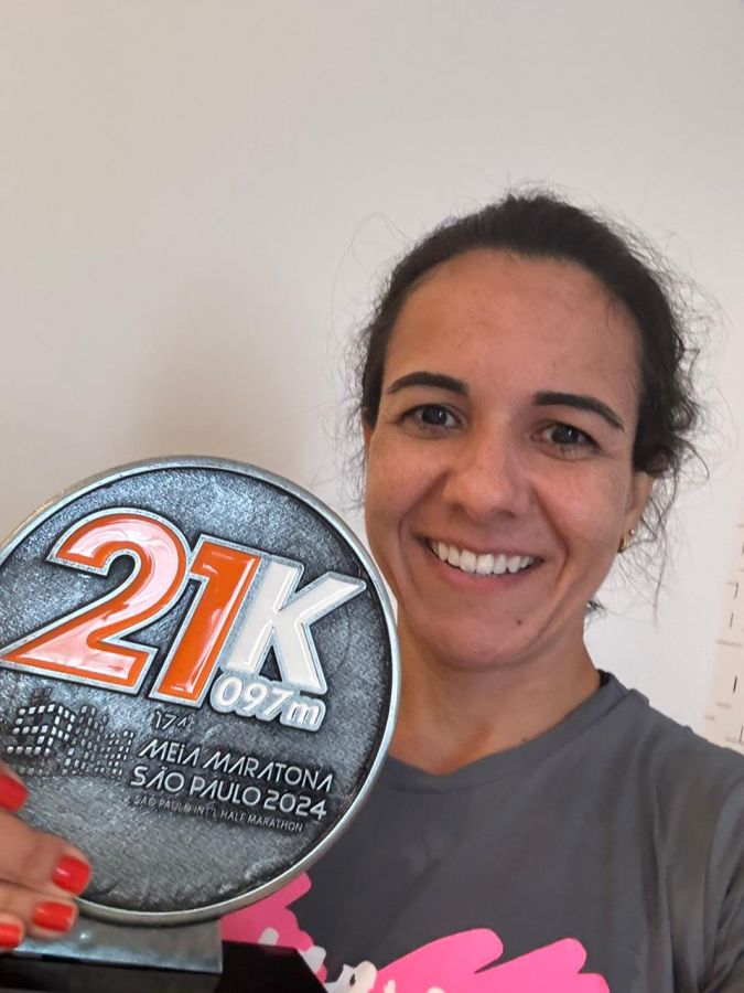 A atleta aparece segurando um trofeu e rindo