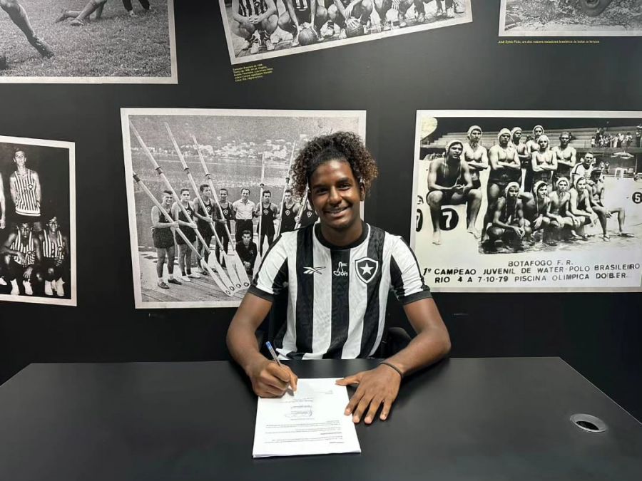 Na foto, o jovem atleta aparece sentado em uma mesa assinando o contrato para jogar no time carioca Botafogo