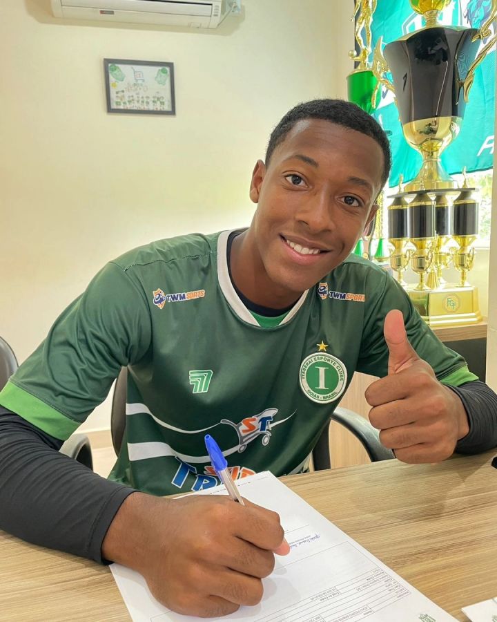 Na foto, o jogador assina o contrato já vestido com a camisa verde do time.