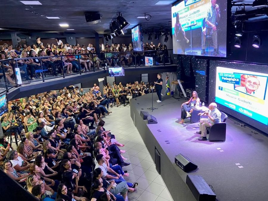 Auditório lotado com palestrantes em tablado