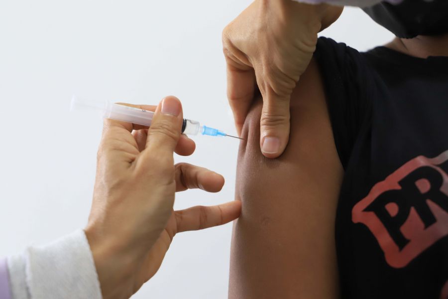 Foto de uma mão com uma seringa aplicando a vacina no braço